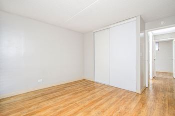  Living room and bedroom of an apartment with wood floors and white walls